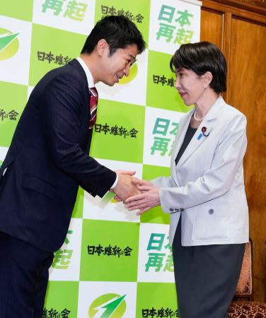 ２０２６年度補正予算案が衆院を通過し、あいさつ回りで日本維新の会の藤田共同代表（左）と握手する高市首相＝４日午後、国会
