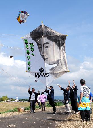 新潟県見附市今町地区と長岡市中之島地区の間を流れる刈谷田川の堤防で行われた「大凧合戦」でたこを揚げる人たち＝６日午後