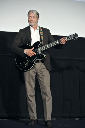 　映画「さよなら、僕の英雄」の舞台あいさつで、ギターを手にポーズをとるマッツ・ミケルセン＝東京都新宿区