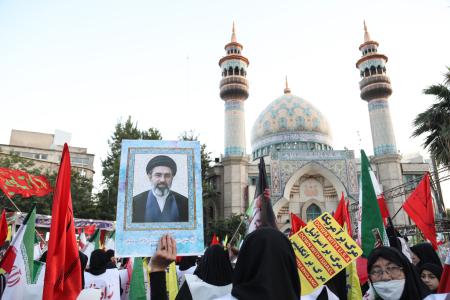 １２日、イラン・テヘランで最高指導者モジタバ・ハメネイ師を支持して国旗を持つ人たち（ゲッティ＝共同）
