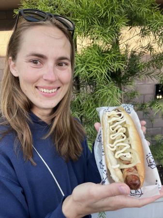 米カリフォルニア州カーソンのサッカースタジアムで、ベーコンが巻かれたソーセージのホットドッグを持つエミリー・ベッカーさん＝５月（共同）