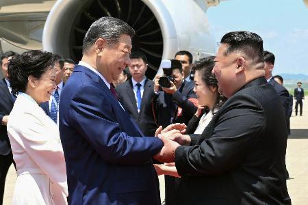 平壌国際空港に到着した中国の習近平国家主席（手前左）を出迎える北朝鮮の金正恩朝鮮労働党総書記＝８日（新華社＝共同）