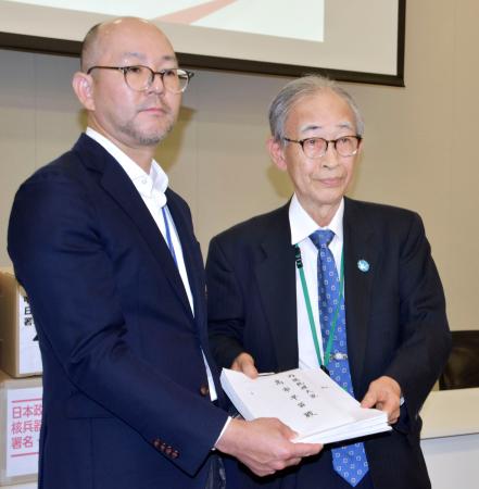 核兵器禁止条約への参加を求める首相宛ての要請書を外務省の松本恭典軍縮不拡散・科学部審議官（左）に手渡す被団協事務局長の浜住治郎さん＝１９日午後、国会