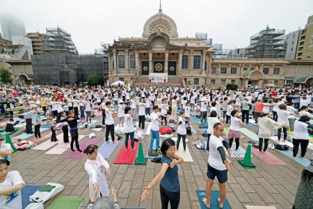 国連が定めた「国際ヨガの日」に、東京都中央区の築地本願寺の境内でヨガを楽しむ参加者=21日午前
