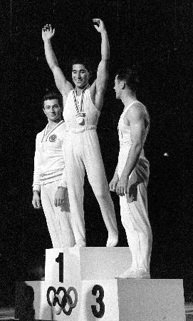1964年10月、東京五輪体操男子種目別の跳馬で金メダルを獲得した松田(旧姓山下)治広さん(中央)=東京体育館