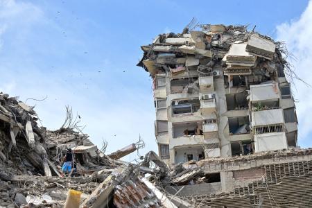 地震で崩落した建物と救出作業=25日、ラグアイラ(ロイター=共同)