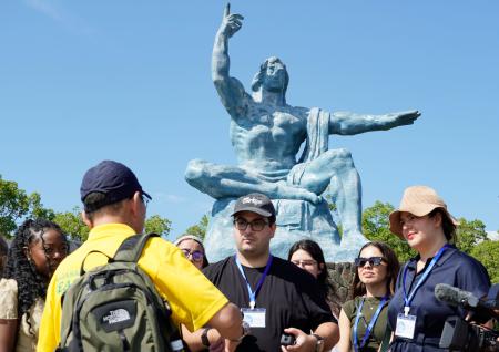 長崎市の平和公園を訪れ説明を受けるスタディーツアーの参加者＝２９日午後