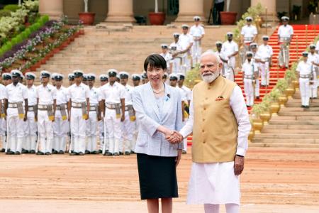 歓迎式典で握手する高市首相(左)とインドのモディ首相=2日、ニューデリー(共同)