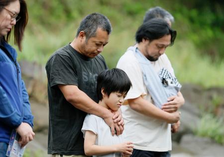 ２０２０年７月の豪雨から６年となり、氾濫で多くの被害をもたらした球磨川に向かい黙とうする人たち＝４日午前、熊本県八代市