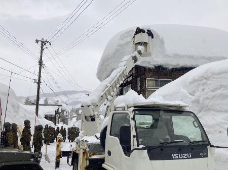 新潟県魚沼市で屋根の雪下ろし作業をする陸上自衛隊員ら＝２月（新潟県提供）