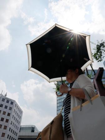 強い日差しの中、福岡市の繁華街で日傘を差して歩く人。気象庁は九州北部が梅雨明けしたとみられると発表した＝８日午後