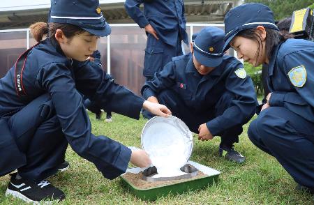 鑑識の授業で、足跡に石こうを流し入れる記者（左）。右は松葉花帆巡査＝６月、長野県警察学校（代表撮影）