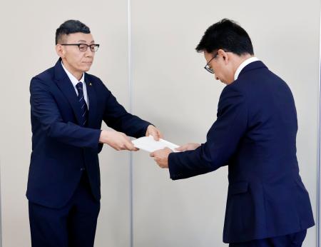 宮城県名取市役所で、第三者委員会の鎌田健司委員長（右）から中学３年の男性の飛び降りに関する報告書を受けとる教育長＝１０日午前