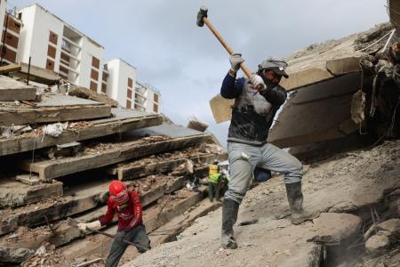 １０日、地震で倒壊した建物のがれきの上で活動する救助隊員＝ベネズエラ・ラグアイラ州（ロイター＝共同）