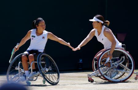 車いすの部女子ダブルス決勝でポイントを奪いタッチを交わす上地結衣(左)、朱珍珍組=ウィンブルドン(共同)
