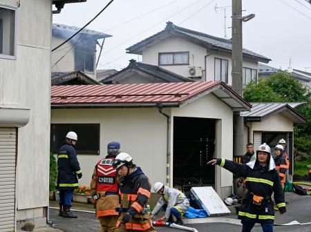 騒然とする秋田県にかほ市の火災現場付近。奥左の住宅から煙が立ち上っていた＝１３日午後１時８分