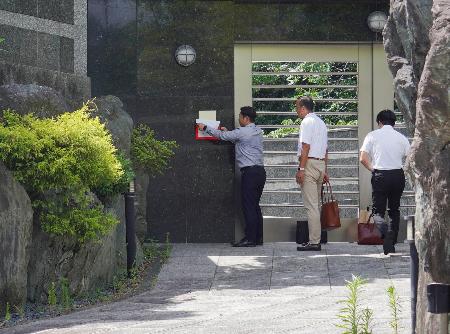 野村悟被告の自宅周辺に貼られた事務所使用制限の標章を剥がす福岡県警の捜査員ら=16日午後、北九州市小倉北区