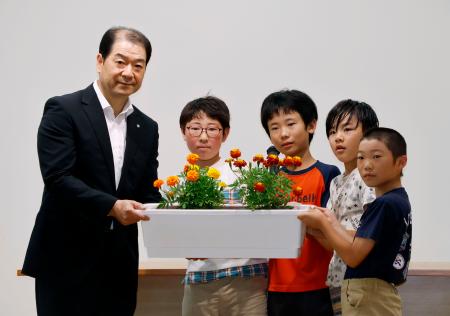 群馬県上野村の村立上野小で、黒沢八郎村長（左端）にマリーゴールドを引き渡す児童たち＝１７日午前