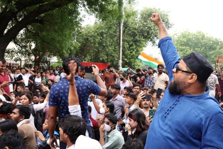 拳を突き上げインドのプラダン教育相辞任を訴えるデモ参加者＝２０日、ニューデリー（共同）