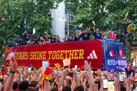 20日、サッカーW杯で優勝したスペイン代表選手らを乗せたバスを歓迎する市民ら=マドリード(共同)