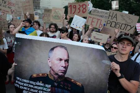 抗議デモでウクライナのシルスキー軍総司令官の肖像を掲げる人=18日、キーウ(AP=共同)