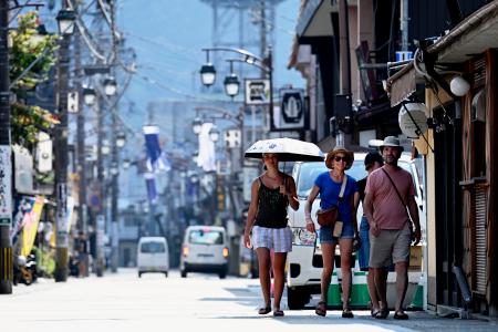 気温４０度を超える「酷暑日」となった岐阜県郡上市内を歩く観光客＝２１日午後