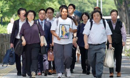 口頭弁論のため、ウィシュマ・サンダマリさんの遺影を手に名古屋地裁に向かう妹のポールニマさん（中央）ら＝２２日午後、名古屋市