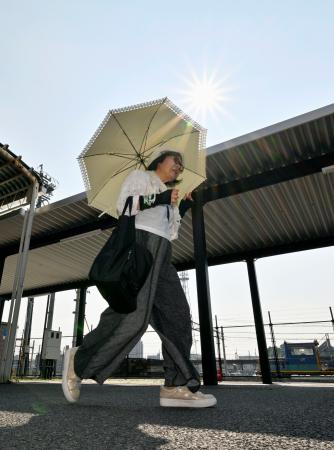 酷暑日となった三重県桑名市で、日傘を差して歩く女性＝２２日午後