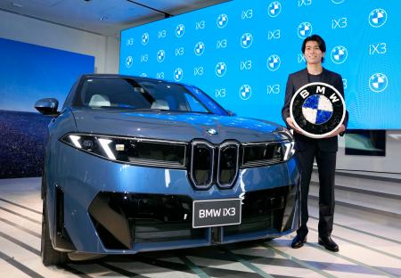 BMWの新型EV「BMW iX3」と写真に納まるサッカー日本代表の中村敬斗選手=22日午後、東京都港区