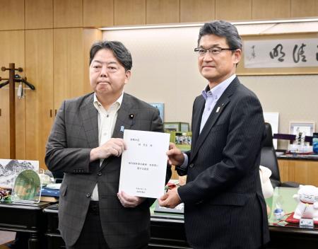 地方税収の偏在是正を求める提言書を林総務相（左）に手渡す宮崎県の河野俊嗣知事＝２２日午後、総務省