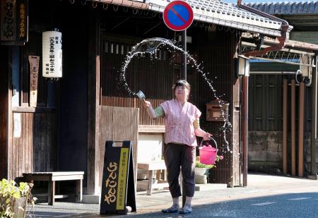 　４０度超えの酷暑日となった岐阜県美濃市で打ち水をする人＝２４日午後