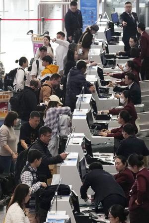 昨年１１月、北京首都空港の日本便などを扱うカウンターで搭乗手続きをする人たち（共同）