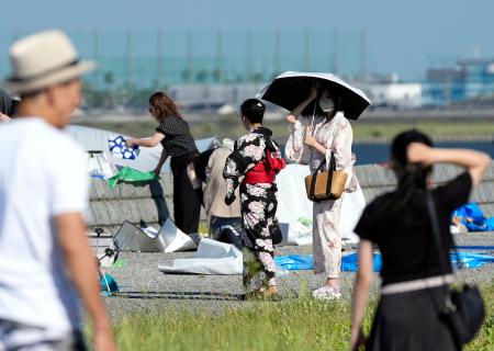 酷暑日となった三重県桑名市で、花火大会の会場周辺に集まった人たち＝２５日午後
