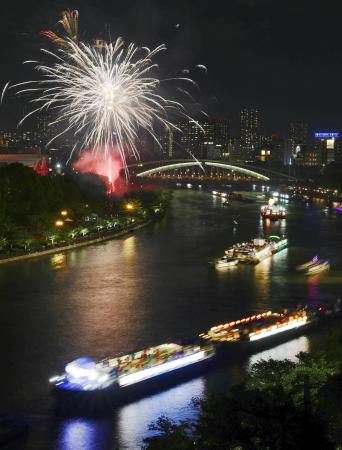 奉納花火が夜空を彩り、大川を船が行き交う天神祭の「船渡御」＝２５日夜、大阪市