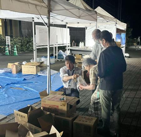 熊本県八代市役所前で住民に水を配る市職員ら＝２８日夜