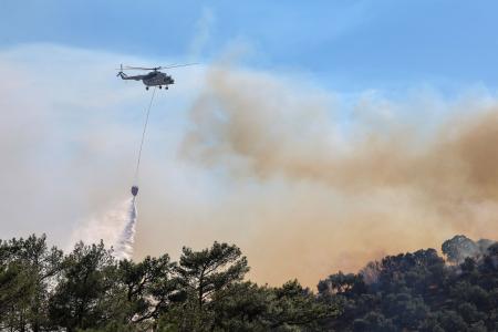 ２９日、ギリシャ・レスボス島で山火事の消火を図るヘリコプター（ロイター＝共同）