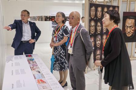 寄港した世界一周クルーズ船内で洋上特別展を見学する（右から）田中稔子さんと広島県被団協の佐久間邦彦理事長＝２８日午前、広島市