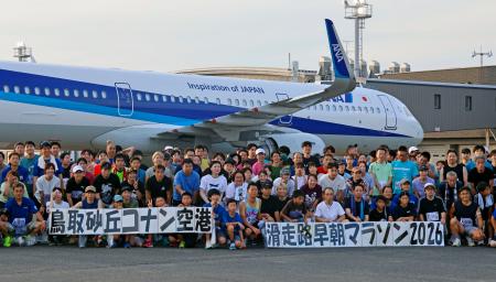 鳥取空港滑走路でのマラソン大会を終え、記念写真に納まる参加者ら＝１日早朝