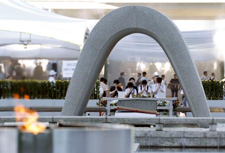 原爆投下から８１年の「原爆の日」を迎え、平和記念公園で原爆慰霊碑に手を合わせる人たち＝６日午前６時２０分、広島市中区