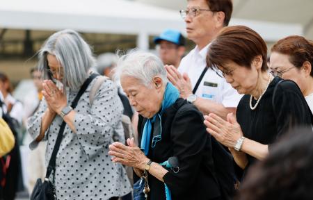 長崎市の平和公園を訪れ、平和祈念像の前で手を合わせる人たち＝９日午後