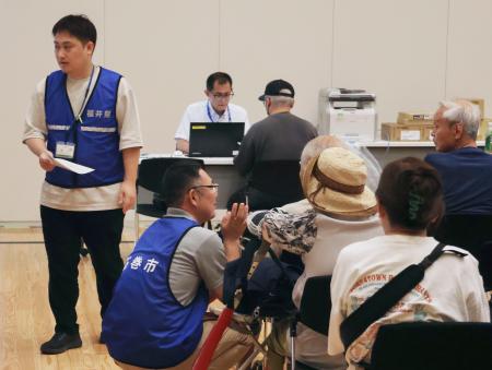 熊本県八代市役所で罹災証明書申請の対応をする、他県から派遣された職員（左端）ら＝１０日午前