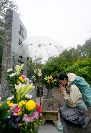日航機墜落事故現場の尾根に立つ「昇魂之碑」で手を合わせる人=12日午前、群馬県上野村