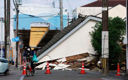 地震で道路をふさぐように倒壊した家屋＝１２日午後、熊本県八代市