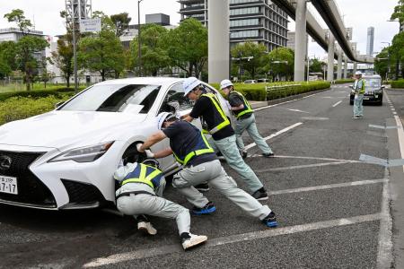 千葉市役所近くの道路で放置車両を脇に寄せる市職員＝１５日午前、千葉市中央区