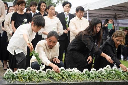15日、フィリピン・ラグナ州カリラヤでの慰霊祭で、並んで献花する参列者ら(共同)