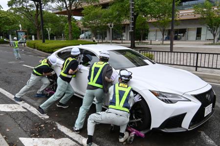 千葉市役所周辺の道路で、放置車両を動かす市職員ら=15日