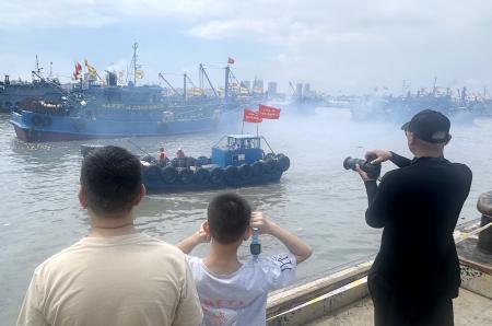 中国福建省石獅市の漁港から出る漁船を眺める人々＝１６日（共同）