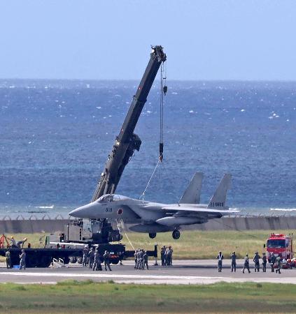 那覇空港の滑走路で立ち往生し、クレーンで引き上げられる航空自衛隊のF15戦闘機=18日午後3時41分