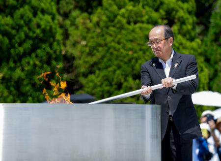 原爆慰霊碑前の「平和の灯」から愛知・名古屋アジア大会の聖火リレーの採火をする広島市の松井一実市長＝２０日、広島市の平和記念公園