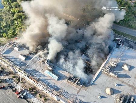 ２１日、ウクライナ・クリブイリフで、ロシア軍の無人機攻撃を受けたショッピングセンターの消火活動（ドニプロペトロウスク州知事のテレグラムから・ロイター＝共同）